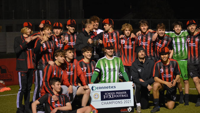 Eine Gruppe von Schülerinnen und Schülern des St. Bede's College posiert mit Pokal und Banner nach dem Fußballmeisterschaftssieg.