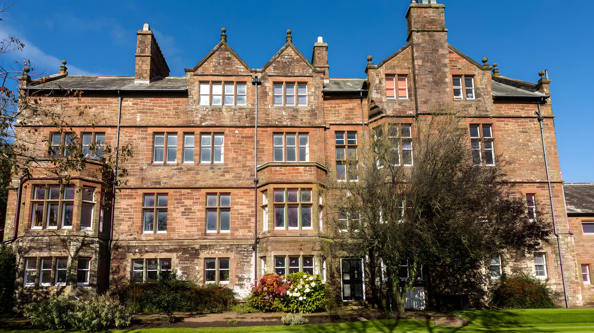 Das historische Backsteingebäude der St. Bees School ist von Bäumen und viel Grün umgeben.