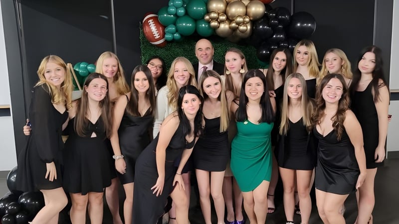 Eine Gruppe junger Frauen in formeller Kleidung posiert vor bunten Luftballons auf dem Gelände der St. Benedict Catholic Secondary School.