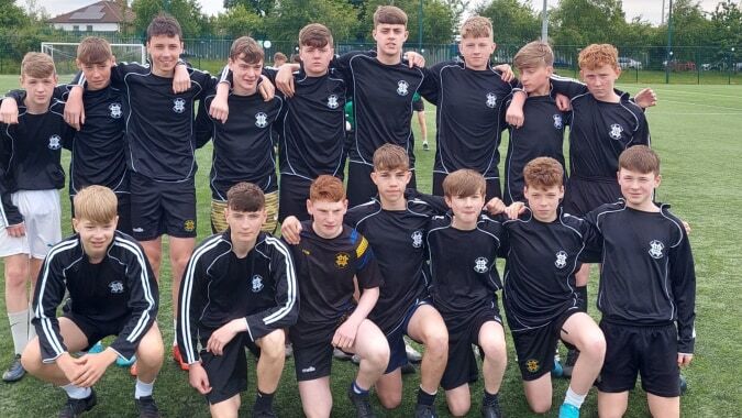 Eine Gruppe von Schülern des St. Benildus College steht in schwarzen Trikots gemeinsam auf dem Fußballfeld.