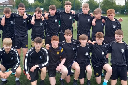 Eine Gruppe junger Fußballspieler in schwarzen Trikots auf dem Sportplatz des St. Benildus College.