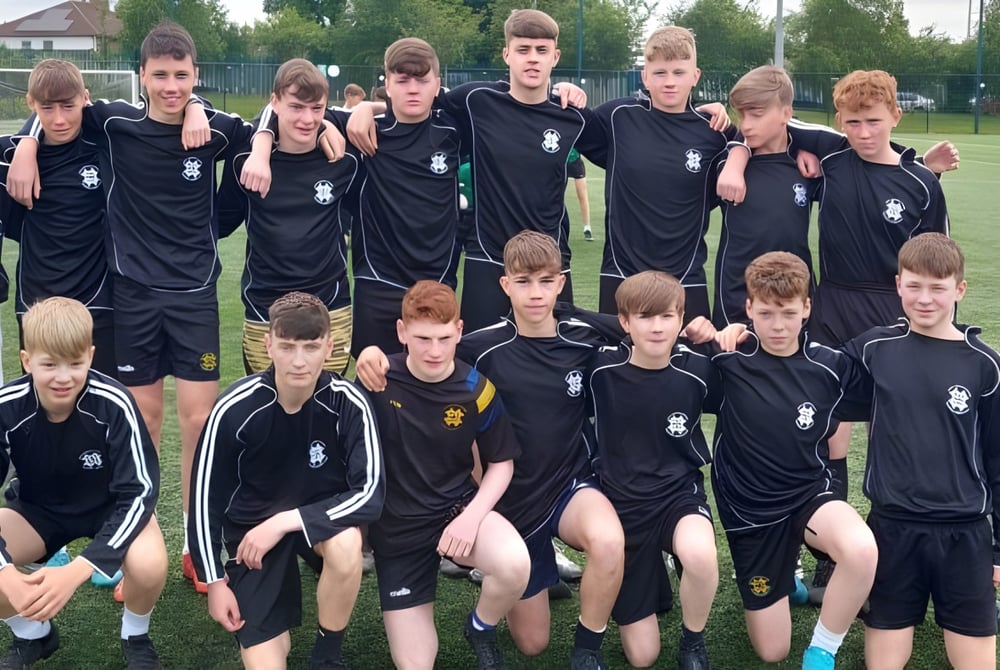 Eine Gruppe junger Fußballspieler in schwarzen Trikots auf dem Sportplatz des St. Benildus College.