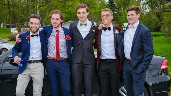 Eine Gruppe Schüler des St. Benildus College steht formal gekleidet vor einem bewaldeten Hintergrund.