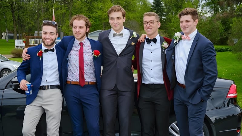 Eine Gruppe Schüler des St. Benildus College steht formell gekleidet im Freien auf einer Wiese mit Bäumen im Hintergrund.