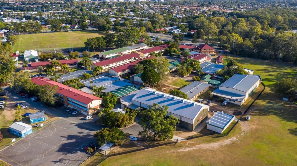 Luftaufnahme des kleinen Ortes mit dem Campus von St. Brendan's College und umliegender Natur.