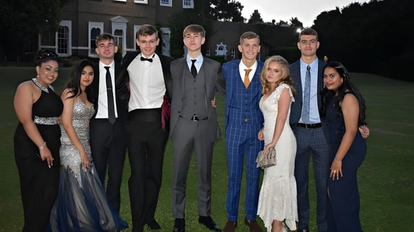 Eine Gruppe von Personen posiert vor dem Gebäude der St. Brendan’s Community School bei einer formellen Veranstaltung.