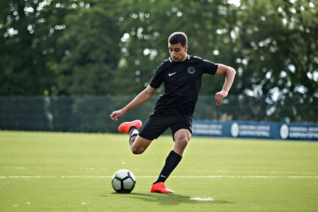 Ein Fußballspieler in einem schwarzen Trikot läuft mit dem Ball auf dem Spielfeld des St. Bricin’s College.