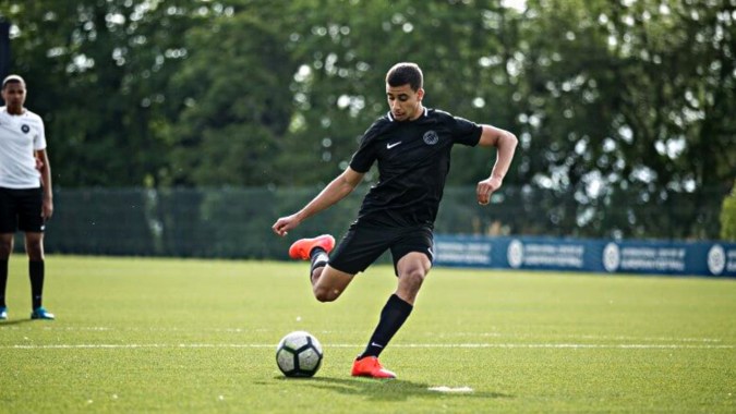 Ein Fußballspieler in schwarzem Trikot dribbelt den Ball auf dem Spielfeld von St. Bricin’s College.