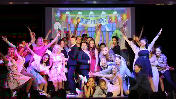 Eine Gruppe junger Frauen führt auf der Bühne des St. Brigid's College vor farbenfrohen Kulissen eine Aufführung auf.