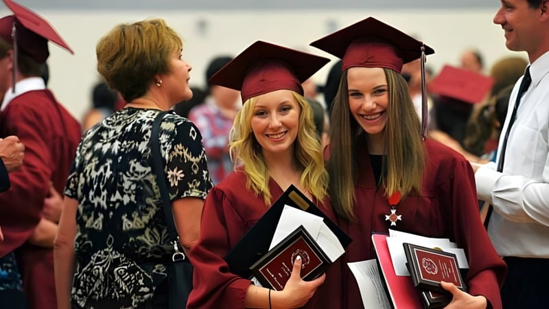 Schülerinnen und Schüler des St. Charles College feiern ihre Abschlussfeier in traditionellen Roben und Hüten.