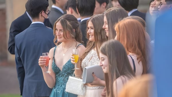 Eine Gruppe gut gekleideter Personen versammelt sich bei einer Feier an der St. Christopher School vor einem Veranstaltungsgebäude.