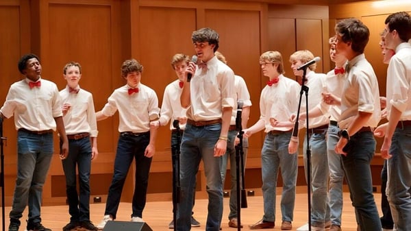 Eine Gruppe Schüler der St. Christopher’s School steht zusammen und führt auf einer Bühne mit Holzverkleidung auf.