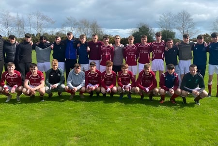 Eine Gruppe von Schülern der St. Ciarán’s Community School posiert gemeinsam auf einem Sportfeld mit Bäumen und bewölktem Himmel im Hintergrund.