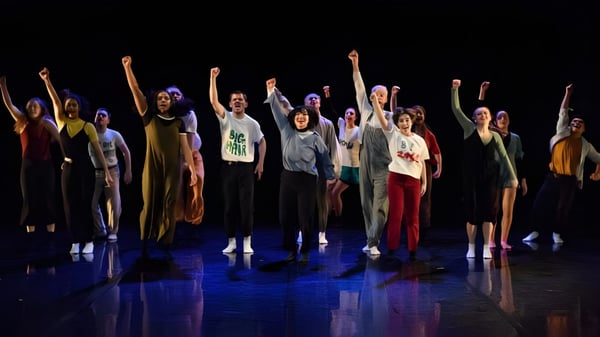 Schüler des St. Coleman's College stehen auf einer Bühne mit erhobenen Armen und führen eine lebendige Performance auf.