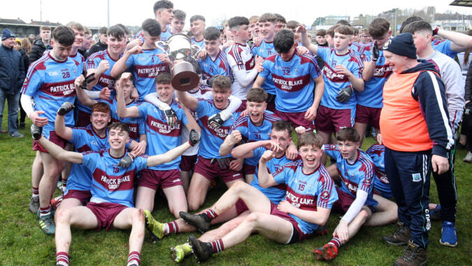 Eine Gruppe junger Athleten des St. Coleman's College feiert gemeinsam mit einem Pokal nach einem sportlichen Erfolg.