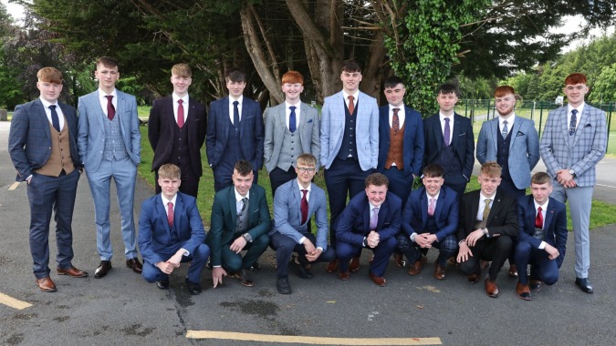 Schüler des St. Coleman's College stehen in formeller Kleidung gemeinsam draußen in einem Park.