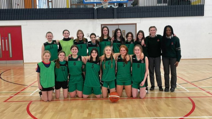 Eine Gruppe junger Basketballspielerinnen posiert auf dem Spielfeld des St. Colman’s Community College.