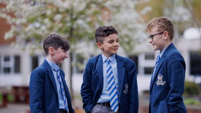 Drei Schüler in Schuluniformen stehen gemeinsam im Garten auf dem Campus des St. Colmans College.