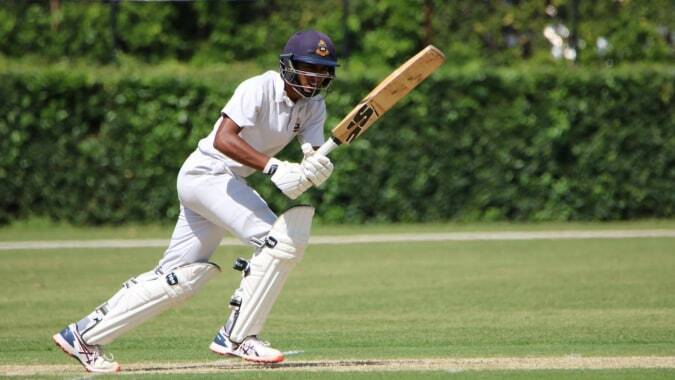 Ein Schüler des St. Columba's College steht auf dem Rasenfeld mit einem Cricket-Schläger und bereitet sich auf das Spiel vor.