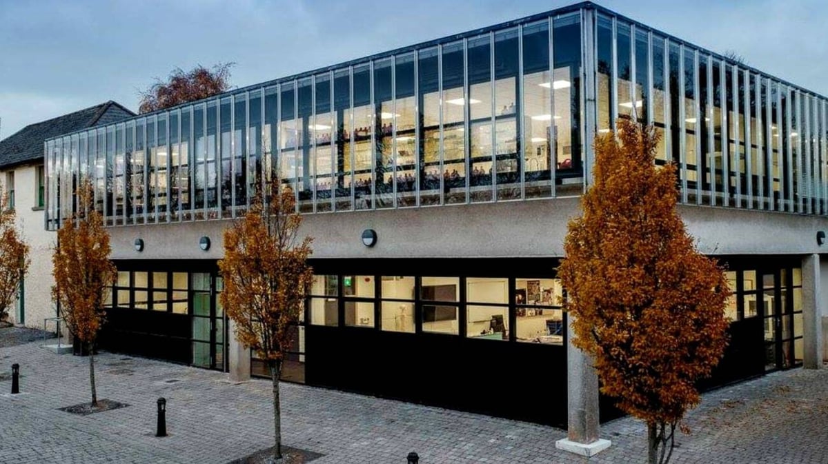 Das moderne Glas- und Stahlgebäude von St. Columba's College ist von herbstlich gefärbten Bäumen umgeben.