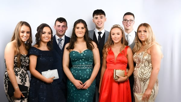 Eine Gruppe gut gekleideter Personen posiert gemeinsam vor weißem Hintergrund am St. Columba's College.