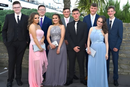 Eine Gruppe von Personen posiert zusammen vor einer Backsteinmauer auf dem Campus von St. Conleths College.