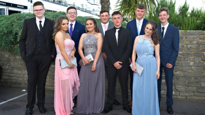 Eine Gruppe gut gekleideter Personen steht vor einem grünen und bebauten Hintergrund auf dem Campus von St. Conleths College.