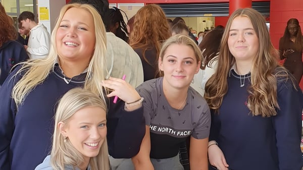 Eine Gruppe lächelnder Schülerinnen trägt blaue Hoodies im Innenbereich auf dem Campus von St. Conleths College.