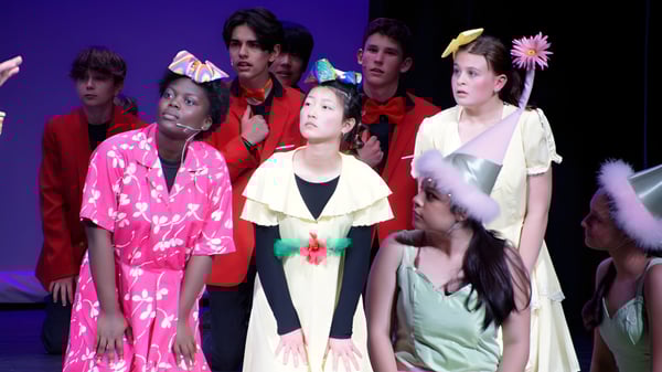 Schüler der St. Croix Lutheran Academy stehen in bunten Kostümen auf einer Bühne mit dunkelblauem Hintergrund.