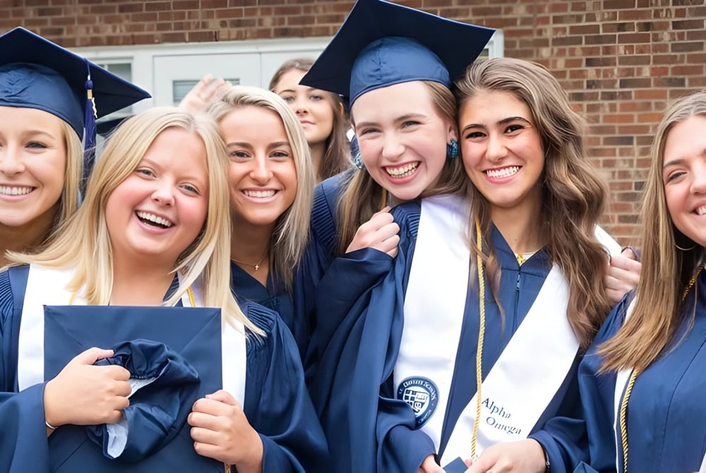 Eine Gruppe von Schülerinnen der St. David Catholic Secondary School steht in Abschlusskleidung vor einem Backsteingebäude und feiert ihren Abschluss.
