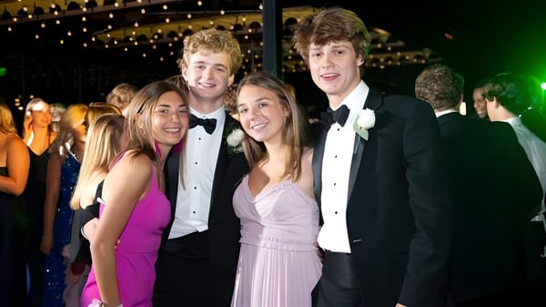 Eine Gruppe Schüler vom St. David’s College posiert gemeinsam in festlicher Garderobe vor einem Hintergrund mit funkelnden Lichtern.