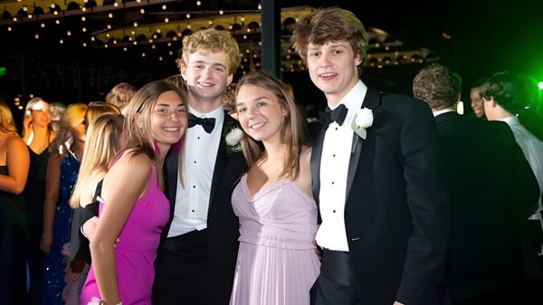 Eine Gruppe von Personen posiert auf einem formellen Event auf dem Campus von St. David’s College vor funkelnden Lichtern.