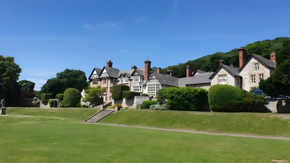 Das historische Herrenhaus mit gepflegtem Garten auf dem Gelände des St. David’s College unter klarem Himmel.