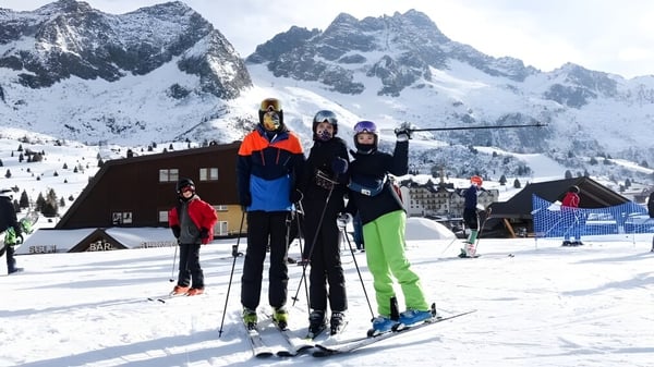 Eine Gruppe von Schülern des St. David's Catholic Sixth Form College posiert vor einer verschneiten Berglandschaft mit Skihütte im Hintergrund.