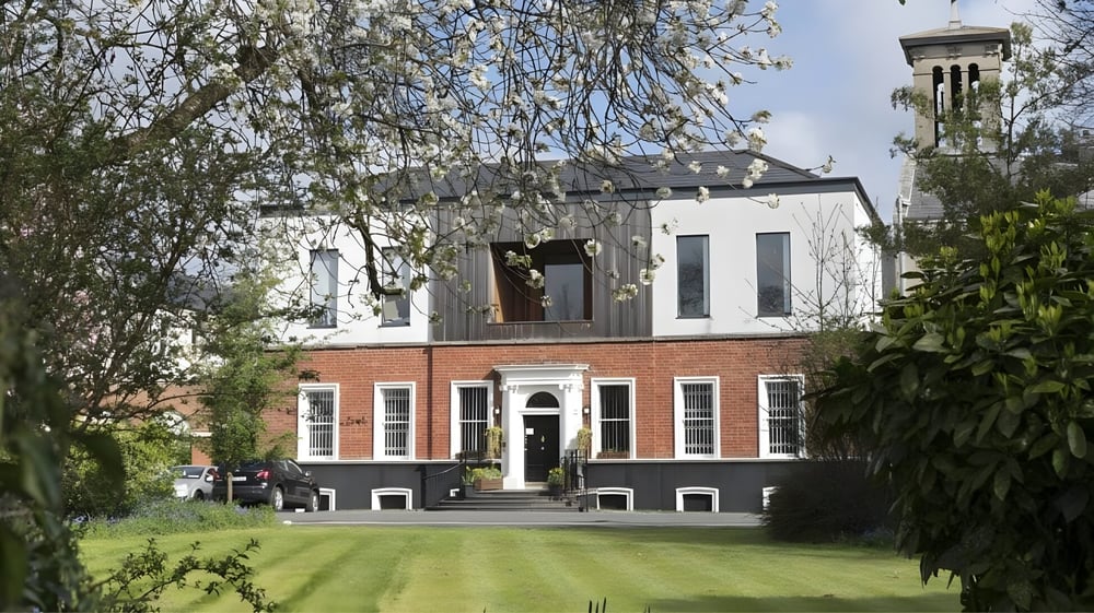 Das Gebäude von St. Dominic’s College mit einem Turm steht umgeben von Grünflächen auf einem gepflegten Rasen.