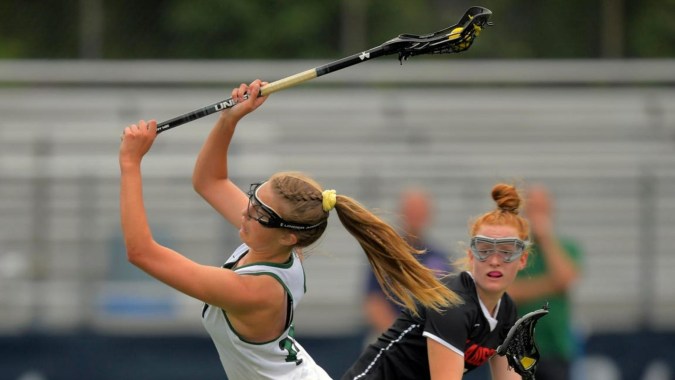 Eine Athletin von St. Dominic’s College greift mit dem Lacrosse-Schläger nach dem Ball auf dem Sportplatz.