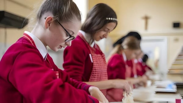 Schüler des St. Dominic’s College tragen rote Roben und sind in einer Gruppendiskussion beschäftigt.