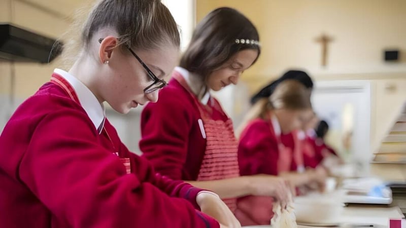 Schüler des St. Dominic’s College tragen rote Roben und sind in einer Gruppendiskussion beschäftigt.