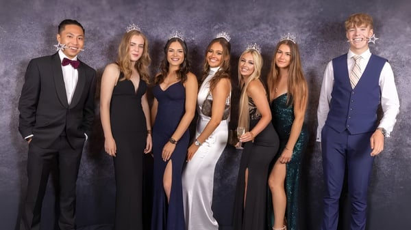 Eine Gruppe von formell gekleideten Personen posiert vor dunklem Hintergrund auf dem Foto der St. Dominic's Grammar School.