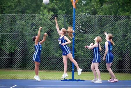 Schülerinnen der St. Dominic's Grammar School führen eine synchronisierte Sportroutine auf einem Tennisplatz aus.