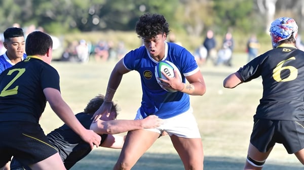 Eine Gruppe Schüler spielt Rugby auf dem Spielfeld des St. Edmund’s College mit Bäumen und Gebäuden im Hintergrund.