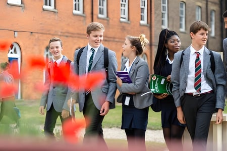 Eine Gruppe Schülerinnen und Schüler steht auf dem Campus von St. Edmund’s College vor einem Backsteingebäude.