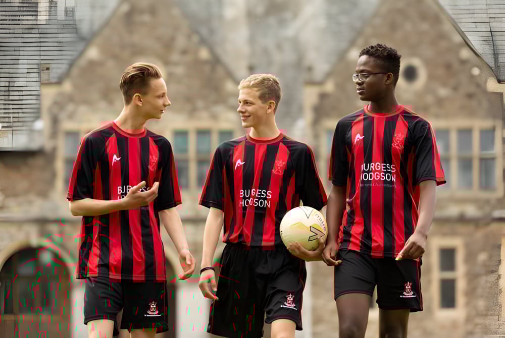 Drei Schüler der St. Edmunds School stehen vor einem historischen Gebäude mit Rundbogenfenstern.