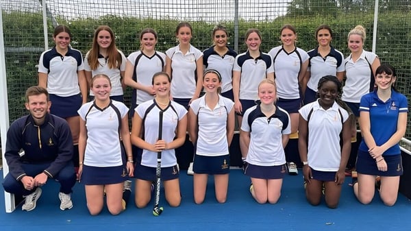Eine Gruppe junger weiblicher Athletinnen posiert auf dem Sportplatz der St Edward's School in Oxford vor einem Drahtzaun.