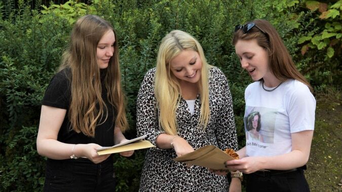Drei Schülerinnen der St. Edward's School in Poole lesen gemeinsam im grünen Außenbereich.