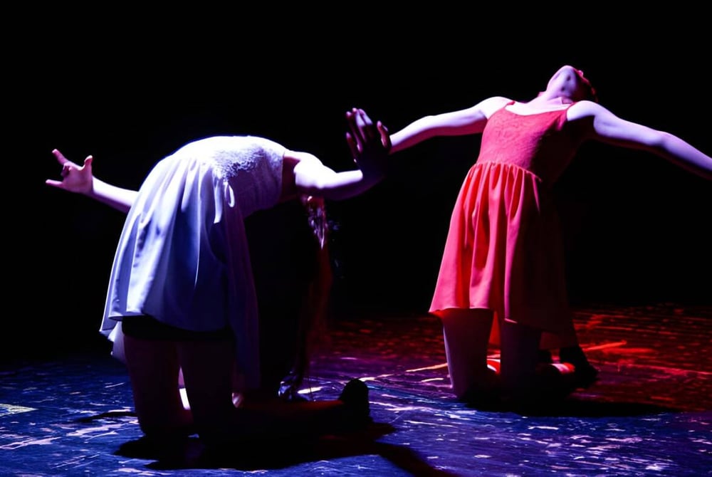 Schüler der St. Edward's School in Poole führen ein dramatisches Theaterstück auf einer Bühne mit gemustertem Boden auf.