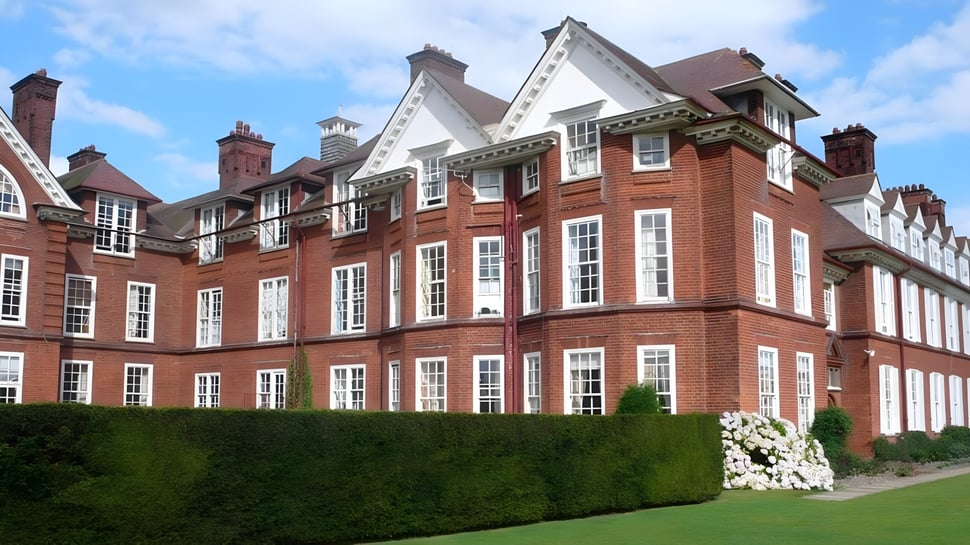 Das historische Backsteingebäude der St. Felix School steht umgeben von gepflegtem Rasen und grüner Umgebung.