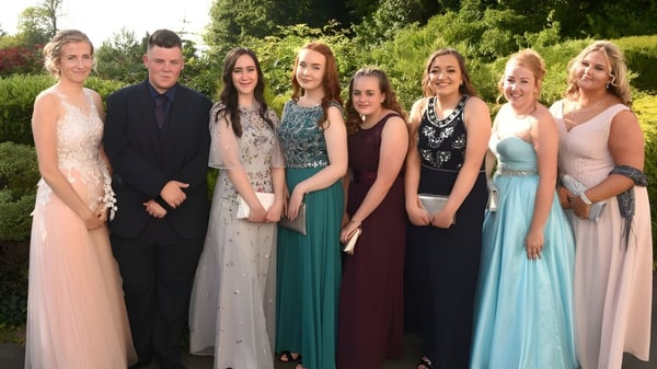 Eine Gruppe elegant gekleideter Personen posiert im Freien auf dem Gelände der St. Felix School.