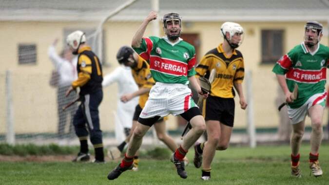 Eine Gruppe von Schülern von St. Fergal’s College spielt Sport auf einem Rasenfeld vor einem Schulgebäude.
