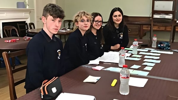 Schüler des St. Finian’s College Mullingar diskutieren gemeinsam an einem Tisch in einem Klassenraum.